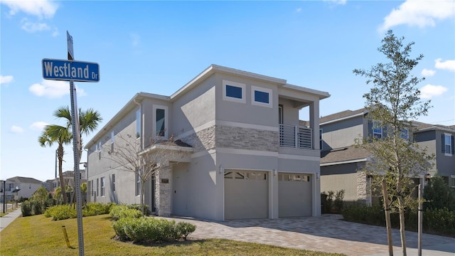 view of front facade with a balcony, a front lawn, and a garage