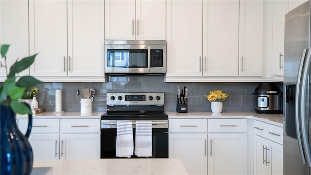 kitchen with white cabinets, backsplash, and stainless steel appliances