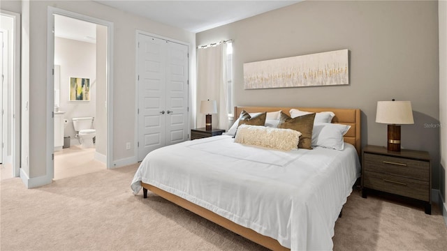 bedroom featuring ensuite bath, light carpet, and a closet