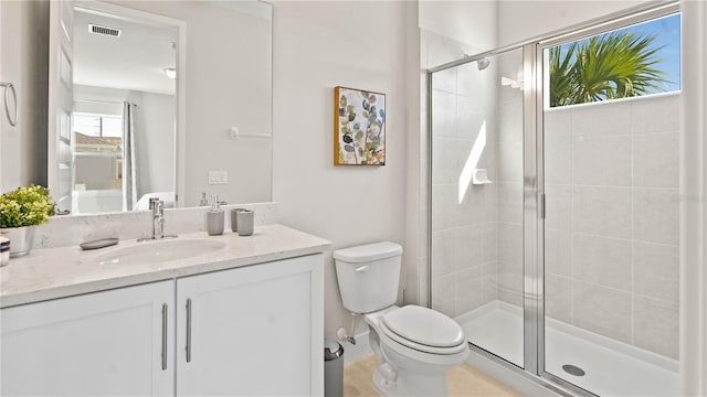 bathroom with tile patterned floors, a shower with door, vanity, and toilet