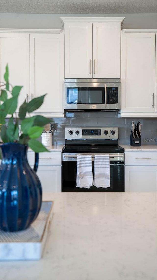 kitchen featuring white cabinets, appliances with stainless steel finishes, and backsplash