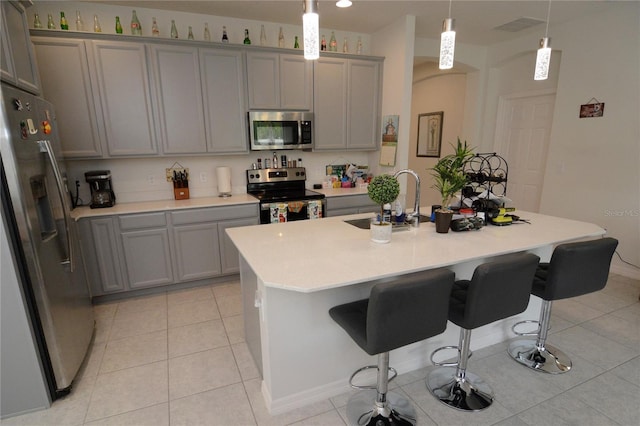 kitchen featuring a center island with sink, pendant lighting, sink, and stainless steel appliances