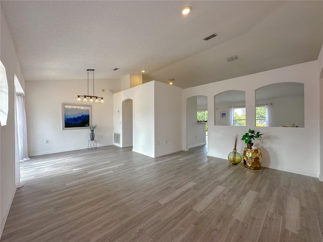 unfurnished living room with a textured ceiling, wood-type flooring, and vaulted ceiling