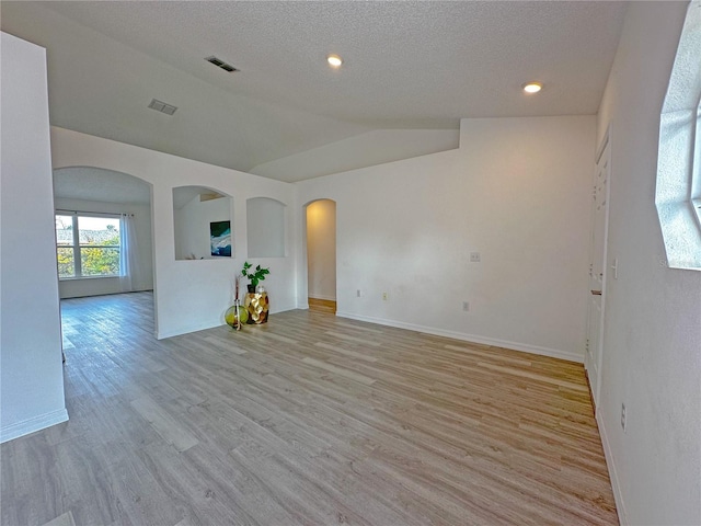 spare room with light hardwood / wood-style floors, lofted ceiling, and a textured ceiling