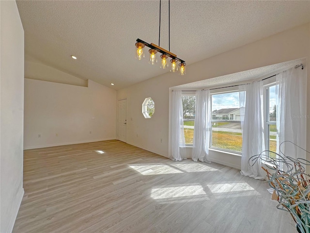 unfurnished dining area with a textured ceiling, light hardwood / wood-style flooring, and lofted ceiling