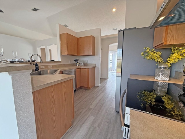 kitchen featuring sink, stainless steel dishwasher, extractor fan, a textured ceiling, and light hardwood / wood-style floors