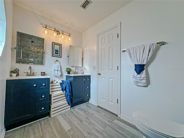 bathroom with a shower, toilet, vanity, and hardwood / wood-style flooring