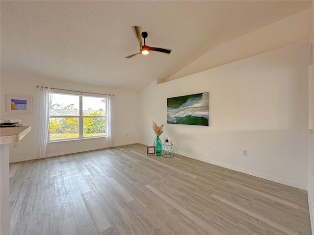 unfurnished room with a textured ceiling, ceiling fan, light hardwood / wood-style floors, and vaulted ceiling