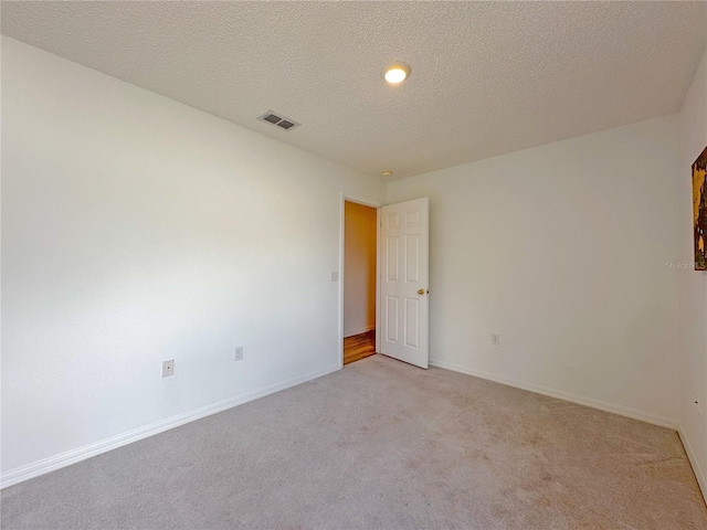 unfurnished room with light colored carpet and a textured ceiling