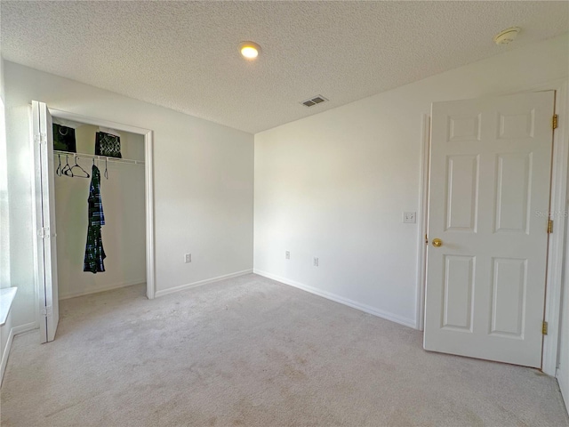 unfurnished bedroom featuring a textured ceiling, light colored carpet, and a closet