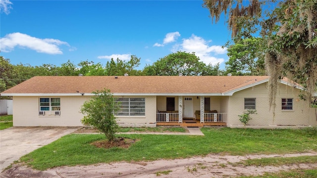 ranch-style home featuring covered porch and a front yard