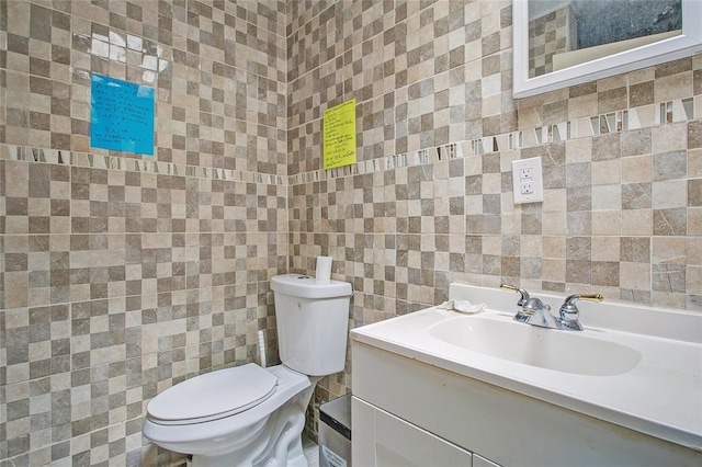 bathroom featuring vanity, toilet, and tile walls