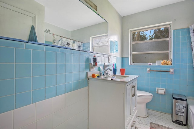 bathroom with curtained shower, tile patterned flooring, toilet, vanity, and tile walls