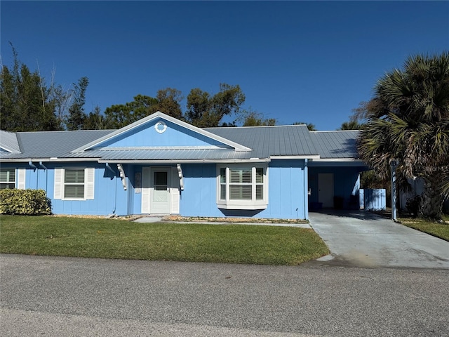 single story home with an attached carport, metal roof, concrete driveway, and a front yard