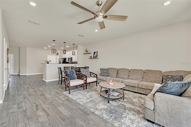 living room featuring ceiling fan and light hardwood / wood-style flooring