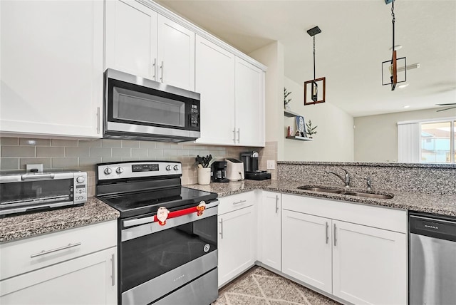 kitchen featuring sink, white cabinetry, dark stone countertops, appliances with stainless steel finishes, and decorative backsplash