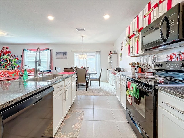 kitchen featuring white cabinets, hanging light fixtures, a wealth of natural light, and black appliances