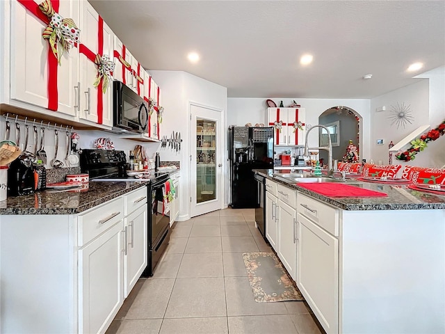 kitchen featuring a kitchen island with sink, white cabinetry, sink, and black appliances