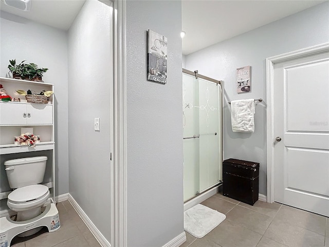 bathroom with tile patterned flooring, toilet, and a shower with door