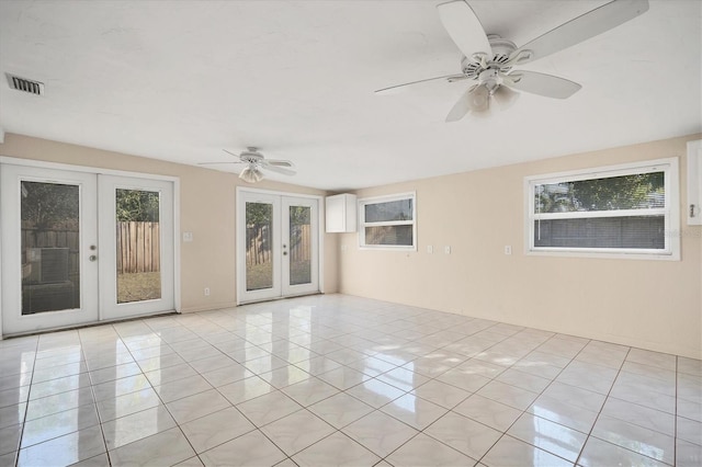 unfurnished room with ceiling fan, a healthy amount of sunlight, light tile patterned floors, and french doors