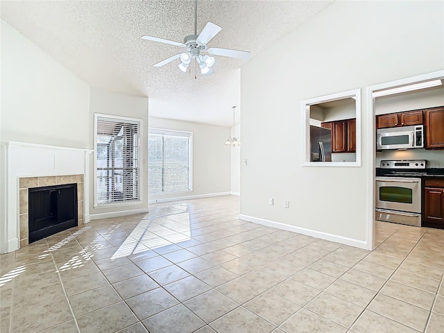 unfurnished living room featuring ceiling fan with notable chandelier, a fireplace, light tile patterned floors, and a textured ceiling