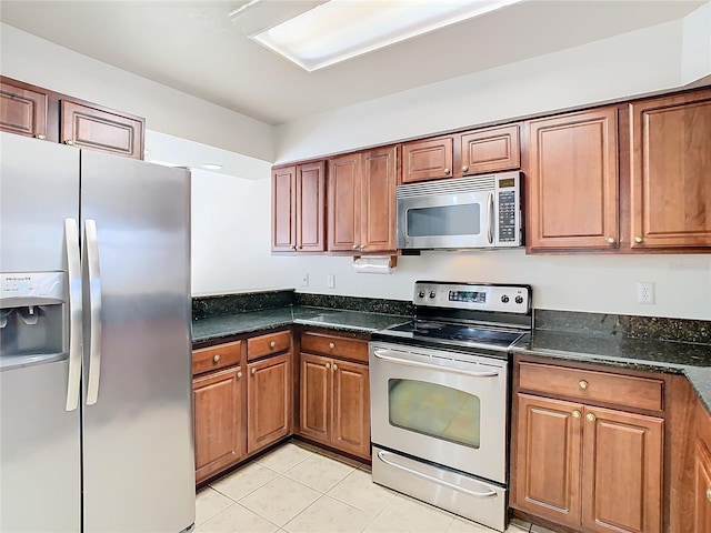 kitchen with light tile patterned flooring, stainless steel appliances, and dark stone counters