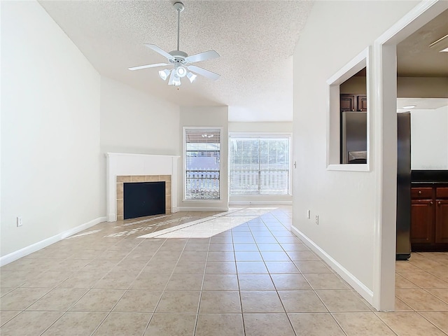 unfurnished living room featuring light tile patterned floors, a textured ceiling, ceiling fan, and a tiled fireplace