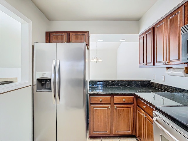 kitchen featuring pendant lighting, stainless steel refrigerator with ice dispenser, dark stone countertops, light tile patterned floors, and a chandelier