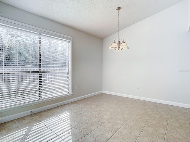 empty room with lofted ceiling, tile patterned flooring, a textured ceiling, and a notable chandelier