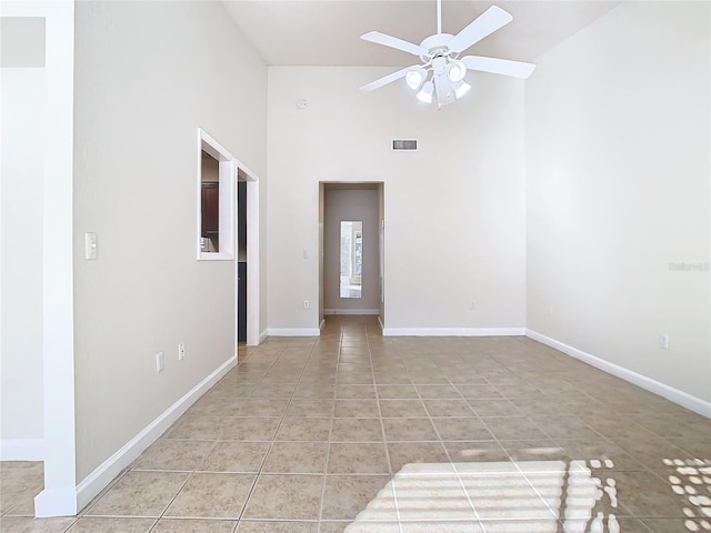 tiled empty room featuring ceiling fan and a high ceiling