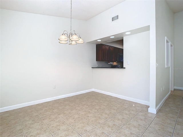 empty room featuring light tile patterned flooring, a towering ceiling, and a chandelier