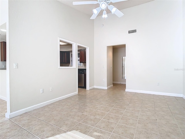 tiled spare room featuring ceiling fan and a towering ceiling