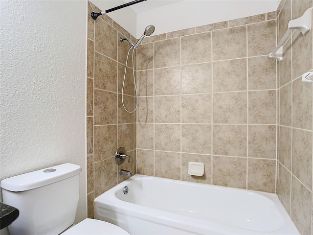 bathroom featuring tiled shower / bath combo and toilet