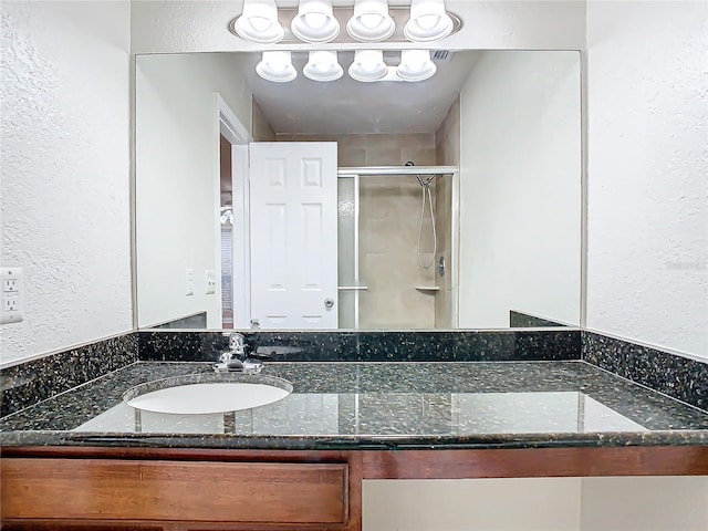 bathroom featuring a shower with door and vanity