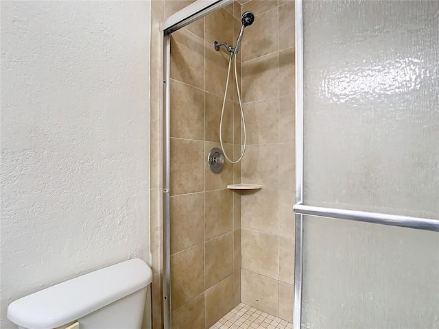 bathroom featuring a shower with shower door and toilet