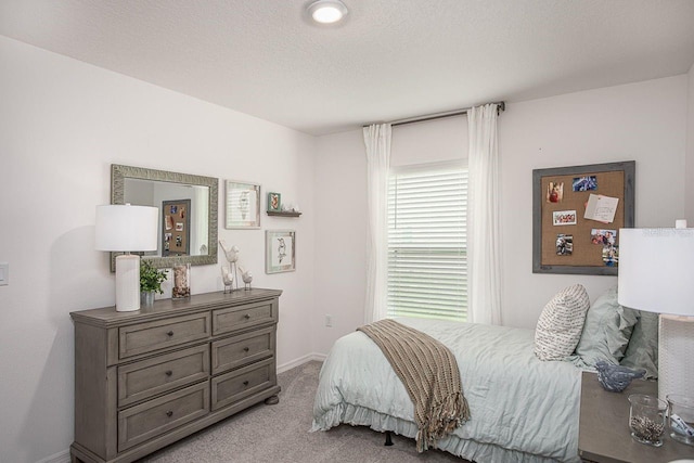 bedroom with light colored carpet and a textured ceiling