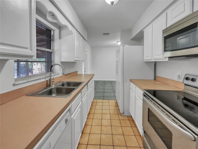 kitchen featuring sink, white cabinetry, stainless steel appliances, and light tile patterned floors