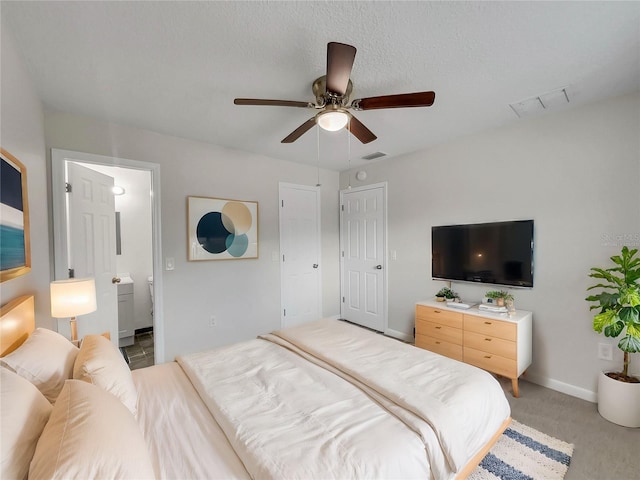 bedroom featuring ceiling fan, carpet floors, ensuite bathroom, and a textured ceiling