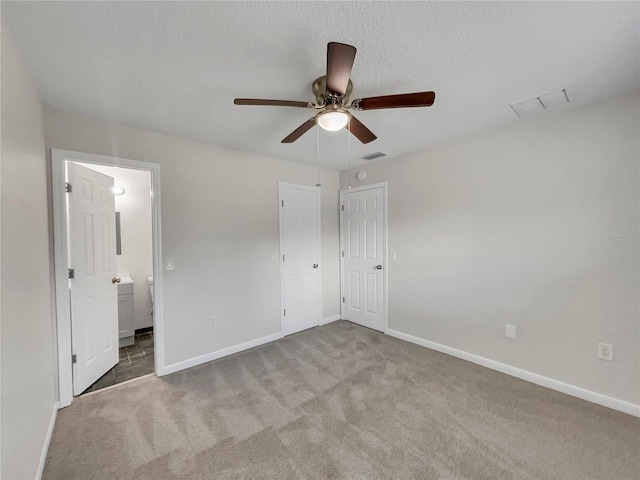 unfurnished bedroom with connected bathroom, ceiling fan, light colored carpet, and a textured ceiling