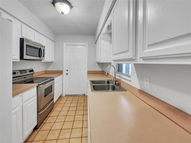 kitchen featuring appliances with stainless steel finishes, a textured ceiling, sink, white cabinetry, and light tile patterned flooring