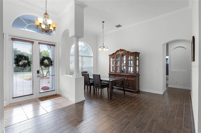 entryway featuring ornate columns, crown molding, a towering ceiling, and a notable chandelier