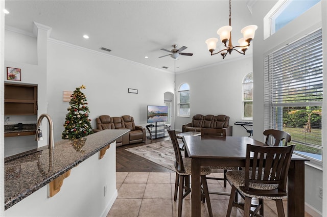 dining room featuring crown molding, light tile patterned floors, and ceiling fan with notable chandelier