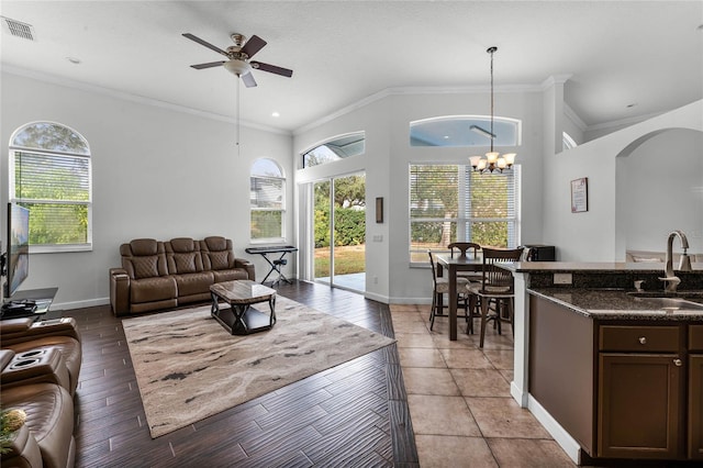 living room with ceiling fan with notable chandelier, crown molding, and sink