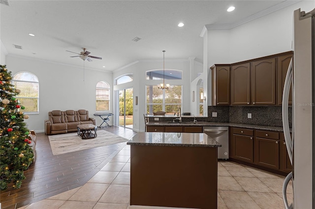 kitchen with a wealth of natural light, crown molding, pendant lighting, light tile patterned floors, and appliances with stainless steel finishes