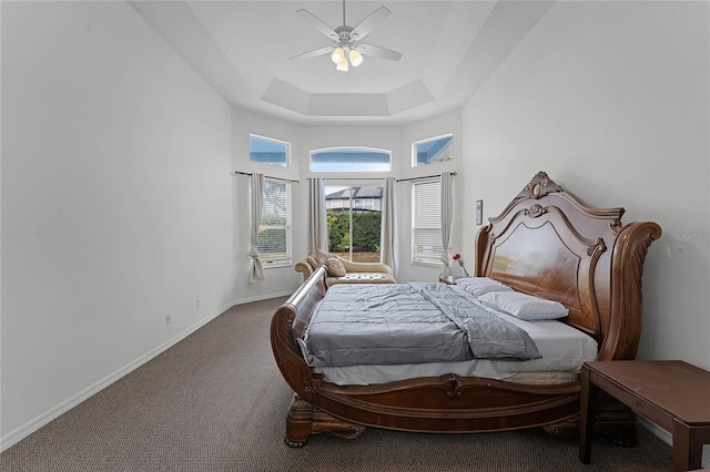 bedroom with carpet flooring, ceiling fan, a raised ceiling, and a high ceiling