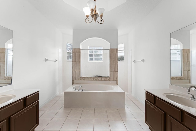 bathroom featuring a chandelier, vanity, tile patterned flooring, and a bathtub