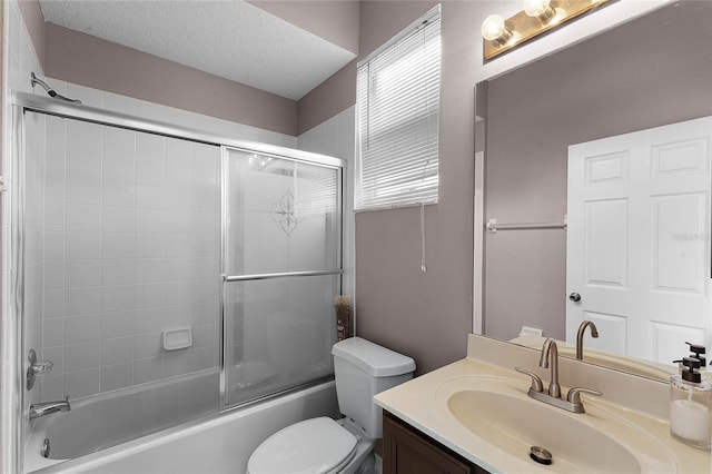 full bathroom featuring vanity, combined bath / shower with glass door, a textured ceiling, and toilet