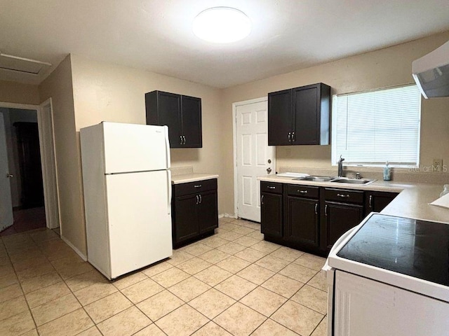 kitchen featuring light tile patterned flooring, stove, sink, range hood, and white fridge