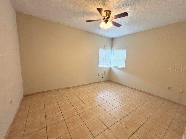 empty room featuring ceiling fan, light tile patterned floors, and a textured ceiling