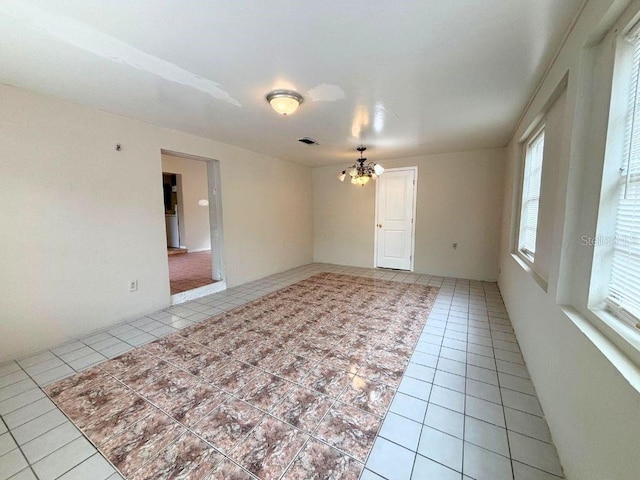 unfurnished room with light tile patterned floors and a notable chandelier